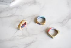 three rings sitting on top of a white marble counter next to a phone charger