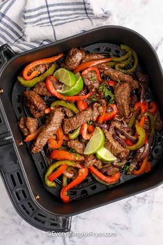 a pan filled with meat, peppers and limes