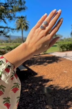 a woman's hand with a ring on it and palm trees in the background