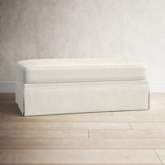 a white bench sitting on top of a hard wood floor in front of a wall