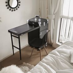 a bedroom with a desk and mirror next to a window in the room that has white curtains on it