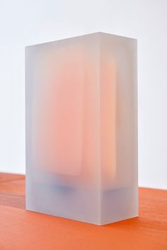 a white cube sitting on top of a wooden table next to an orange countertop