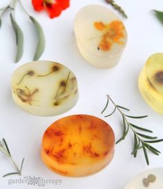 four different types of soaps sitting on top of a white surface next to flowers