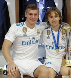 two young men sitting next to each other holding a trophy and posing for the camera