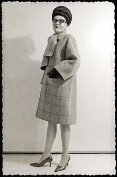 an old black and white photo of a woman in a dress with a hat on her head