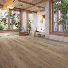 an empty living room with wood floors and large windows overlooking the trees in the background