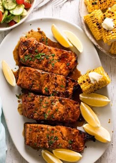 grilled salmon and corn on the cob with lemon wedges