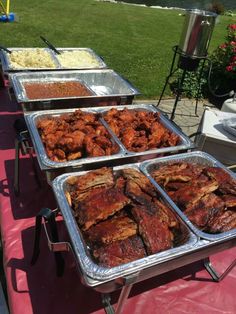 several trays of food sitting on top of a pink tablecloth covered picnic table