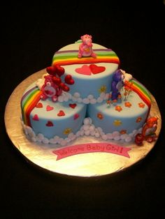 a three tiered cake with teddy bears and hearts on the top is decorated in blue frosting