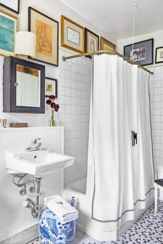 a white bathroom with blue and white tiles on the floor, shower curtain, sink and mirror