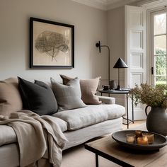 a living room filled with furniture and a painting hanging on the wall above it's windows