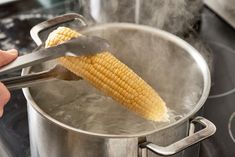 a person is stirring corn on the cob in a pot