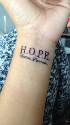 a woman's wrist tattoo with the word hope written on her left arm and an inscription that reads hope