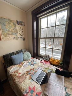 a laptop computer sitting on top of a bed next to a window with lots of papers