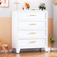 a white chest of drawers in a room with pink and orange wall art on the walls