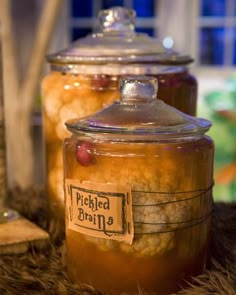 two glass jars filled with food sitting on top of a fur covered table next to a potted plant