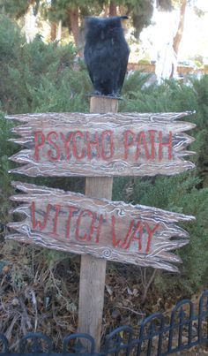 a black bird sitting on top of a wooden sign