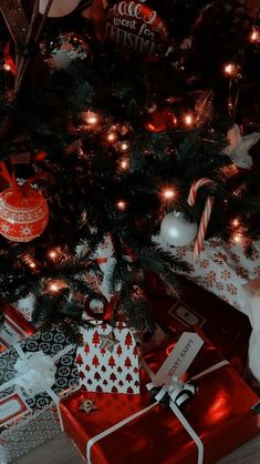 a christmas tree with presents under it on the floor next to a red and white present box