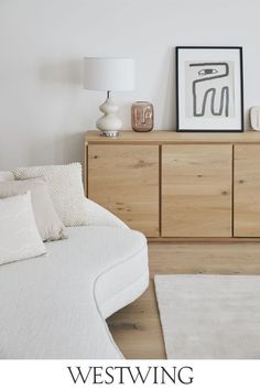 a white bed sitting in a bedroom next to a wooden dresser with pictures on it