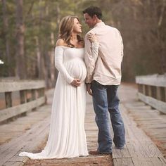 a pregnant woman and man standing on a bridge with the caption zuomn