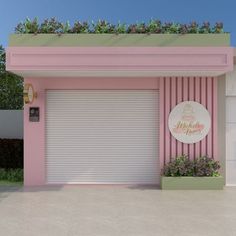 a pink and green building with flowers on the top window sill in front of it