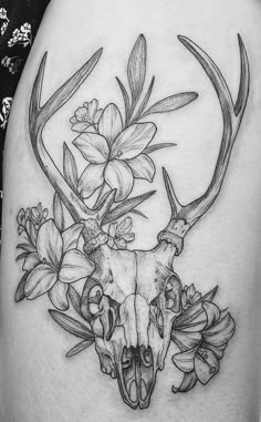 a woman's thigh with a deer skull and flowers on it