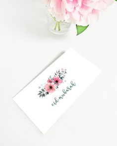 a pink flower in a vase next to a white card with the word beautiful written on it