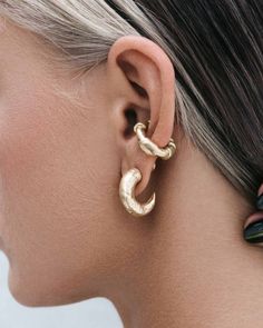 a close up of a person wearing gold earring with an ear clip in the shape of a crescent