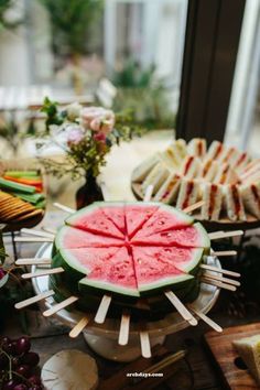 watermelon slices and skewers are arranged on a platter in front of a window