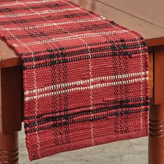 a red and black table runner sitting on top of a wooden table next to a chair