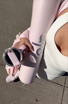 a woman in pink sports bra and leggings holding a water bottle with her right hand