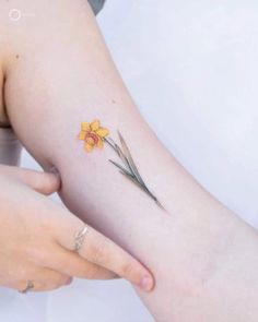 a woman with a yellow flower tattoo on her arm