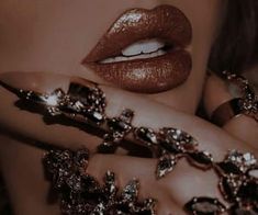 a close up of a woman's face with jewelry on her hands and lips