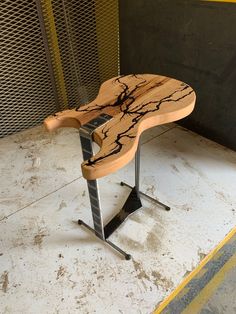 a wooden bench sitting on top of a metal stand next to a yellow and black wall