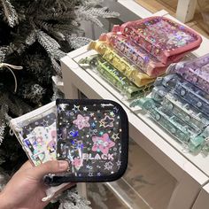 a person holding an item in their hand near some christmas trees and other items on a table