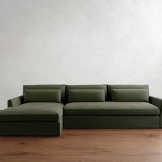 a green couch sitting on top of a hard wood floor next to a white wall