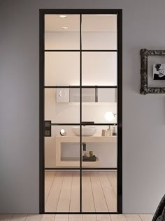 an open door leading into a bathroom with white walls and wood flooring on the side