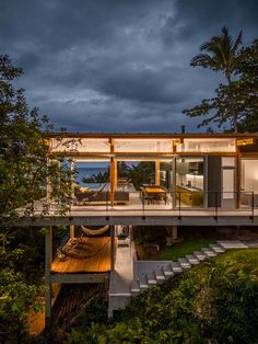 the house is surrounded by lush green trees and has a deck that leads to an outdoor dining area