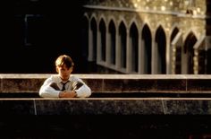 a young man sitting on top of a stone bench