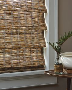 a window with bamboo blinds and a potted plant next to it on a table