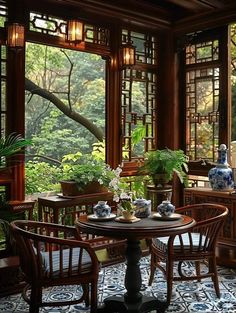 a dining room table with chairs and vases on it in front of large windows