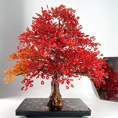 a red tree sitting on top of a table next to a vase filled with flowers