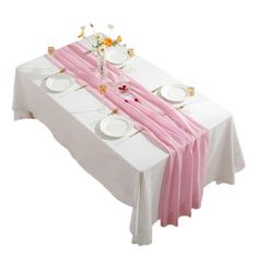 the table is set with white plates and pink napkins