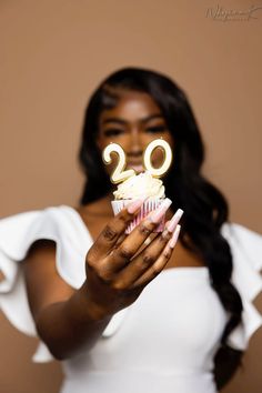 a woman holding up a cupcake with the number twenty on it