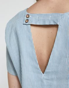 the back of a woman's blue and white striped shirt with a cut out shoulder