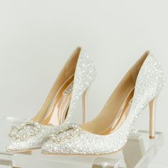 a pair of white high heeled shoes sitting on top of a table