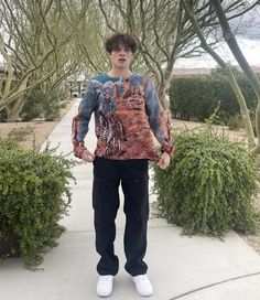 a young man standing on a sidewalk with his hands in his pockets and wearing a shirt with an image of a tiger