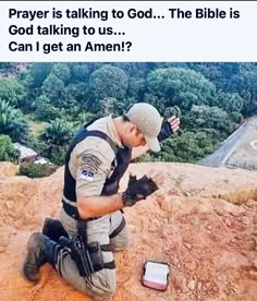 a man kneeling down on top of a dirt hill next to a cell phone and an american flag