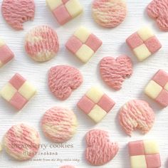 pink and white cookies are arranged on a table