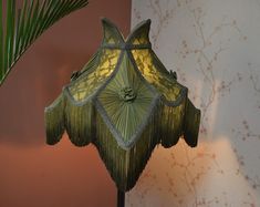 a green lamp sitting on top of a table next to a potted palm tree